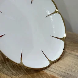 Ceramic serving plate with a white wooden base and golden edges - circular - large